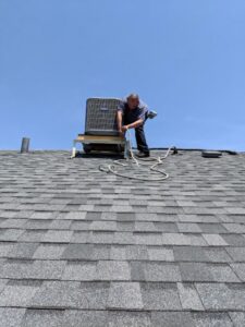 An HVAC technician from Deljo Heating, Cooling & Plumbing repairing a residential rooftop AC unit in Chicago, IL.