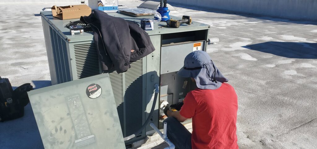 An HVAC technician repairing a commercial rooftop AC unit for Hurn Mechanical Heating & Cooling in El Cajon, CA.