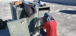 An HVAC technician repairing a commercial rooftop AC unit for Hurn Mechanical Heating & Cooling in El Cajon, CA.