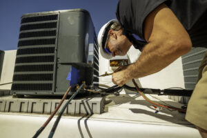 An HVAC technician performing repairs on a rooftop air conditioning unit for Reed's Heating & Cooling in Toms River, NJ.