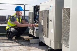 An HVAC technician repairing a rooftop commercial unit for Glendale HVAC in Glendale, AZ