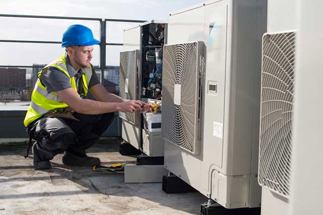 An HVAC technician repairing a rooftop commercial unit for Glendale HVAC in Glendale, AZ