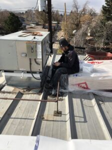 An HVAC technician repairing a commercial rooftop unit for 5280 Cooling Heating & Refrigeration in Lakewood, CO