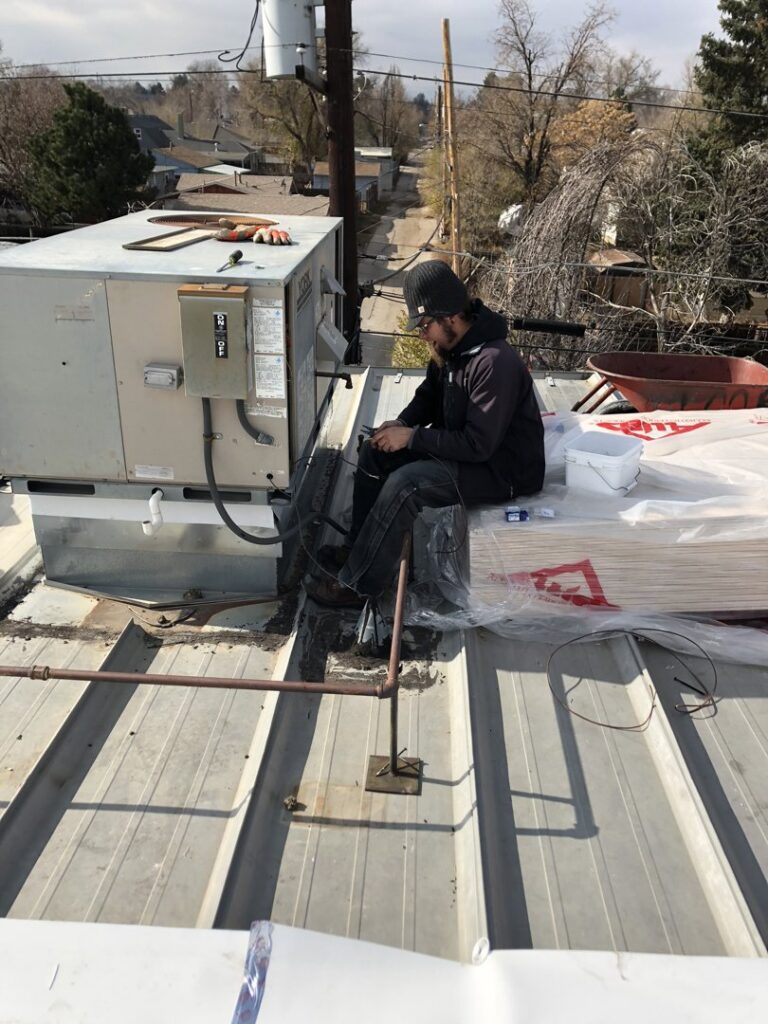 An HVAC technician repairing a commercial rooftop unit for 5280 Cooling Heating & Refrigeration in Lakewood, CO
