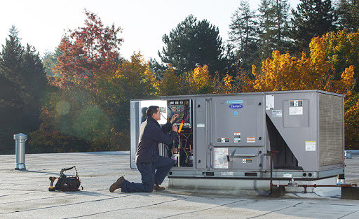 An HVAC technician performing maintenance or repair on a large commercial rooftop unit for Breeze Heating & Cooling Nashville in Nolensville, TN.