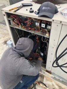 An HVAC technician repairing the internal components of a commercial rooftop unit for QuesTec in Columbia, MO
