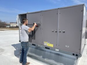 A Wes-Tech Services HVAC technician repairing a commercial rooftop unit in Bloomington, IN.