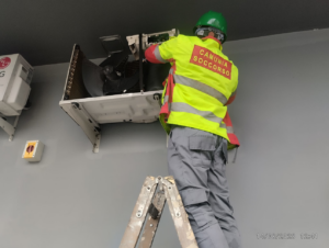 A Facilityfix technicians' HVAC contractor on a ladder repairing an LG split AC unit in Port Harcourt, NG.