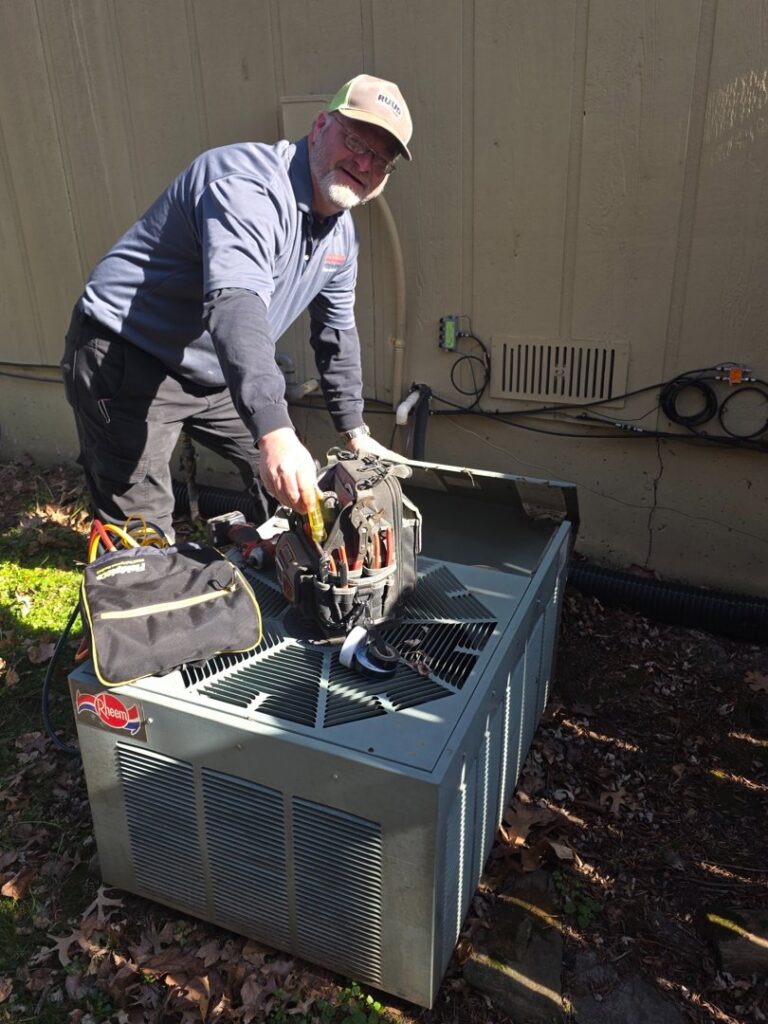 An HVAC technician from Symbiont Services repairing an outdoor condenser unit in Englewood, FL.