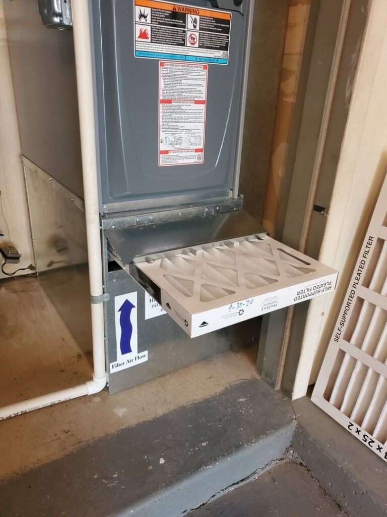 An HVAC technician replacing an air filter in a furnace unit for AccuMax Incorporated in Aurora, IL.
