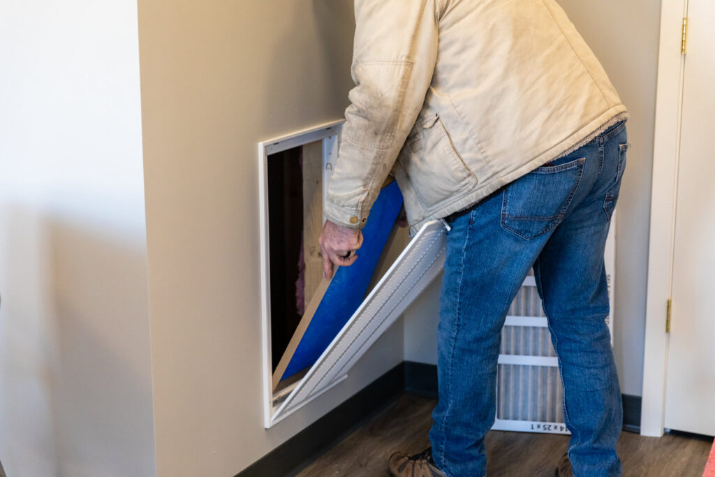 An HVAC technician replacing a dirty air filter in a residential system for Comfort Engineering Co Inc in Tupelo, MS