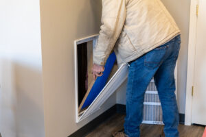An HVAC technician replacing a dirty air filter in a residential system for Comfort Engineering Co Inc in Tupelo, MS