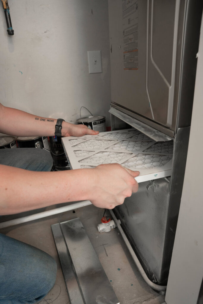 An HVAC technician from CSA HVAC Services replacing an air filter in a furnace in Orem, UT.