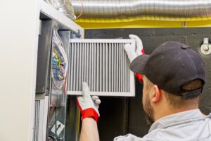 An HVAC technician replacing an air filter in a furnace for G.M. AIR Conditioning & Heating in Wichita, KS.