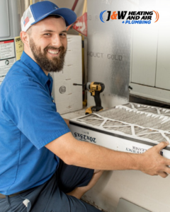 An HVAC technician replacing an air filter during a service call for J&W Heating and Air + Plumbing in Jacksonville, FL.