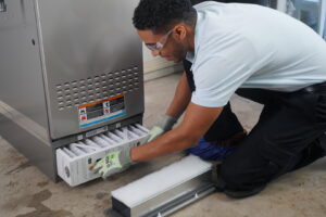 An HVAC technician from McElroy Service Experts replacing an air filter in an indoor unit in Grand Island, NE.