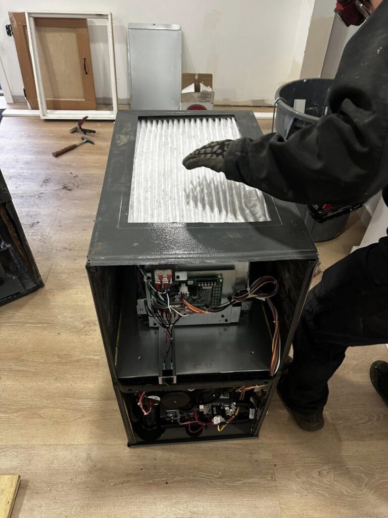 An HVAC technician replacing a furnace filter during maintenance for JN Heating & Cooling in Eure, NC