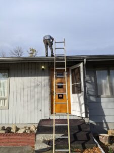 An HVAC technician on a residential roof performing work, likely on a vent, for Arrowseal of Billings HVAC in Billings, MT.