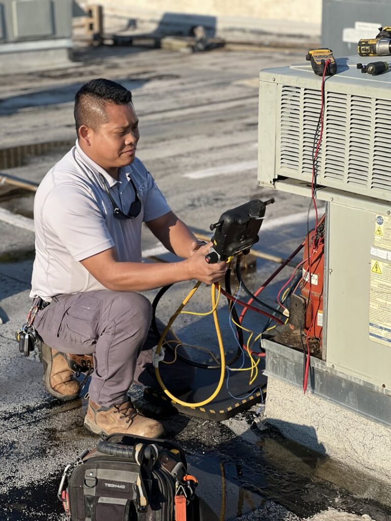 An HVAC technician performing repair and maintenance on a rooftop AC unit for OKIE Heating and Cooling in Tulsa, OK.