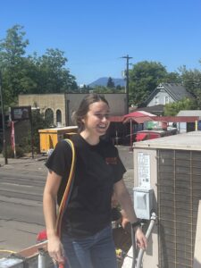 An HVAC technician performing service on a rooftop air conditioning unit for Awesome Air Heating and Cooling LLC in Corvallis, OR.