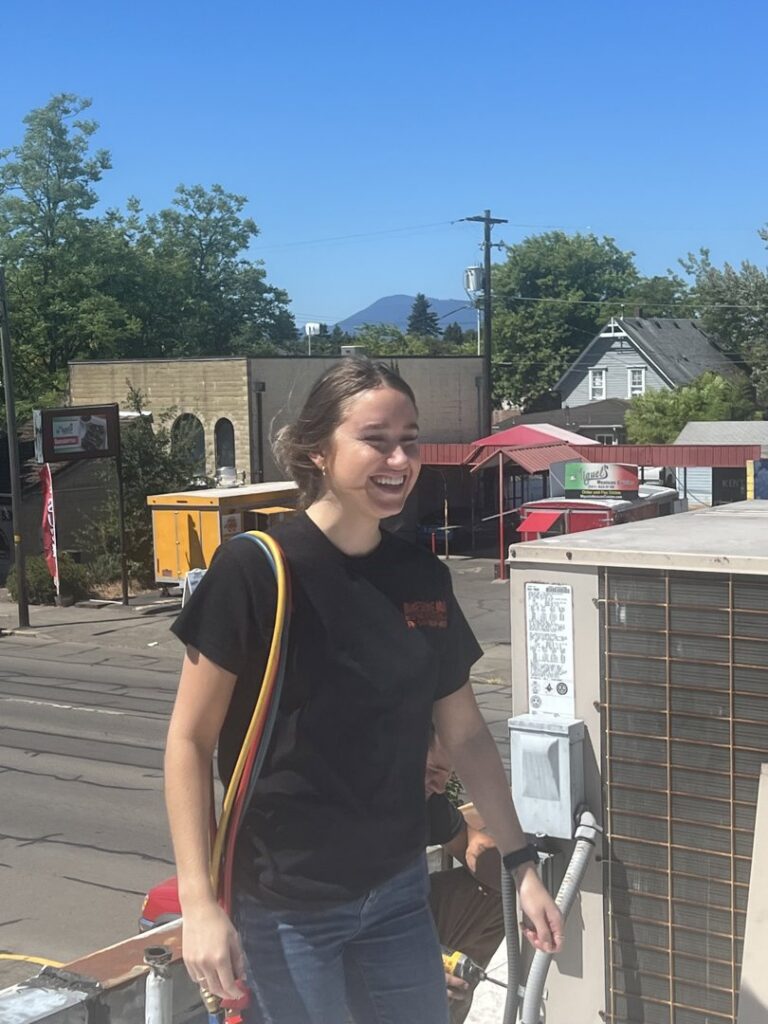 An HVAC technician performing service on a rooftop air conditioning unit for Awesome Air Heating and Cooling LLC in Corvallis, OR.