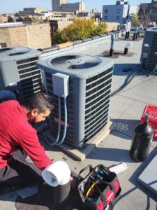 An HVAC technician performing service on a rooftop AC unit for Brothers Heating & Cooling Inc. in Chicago, IL.