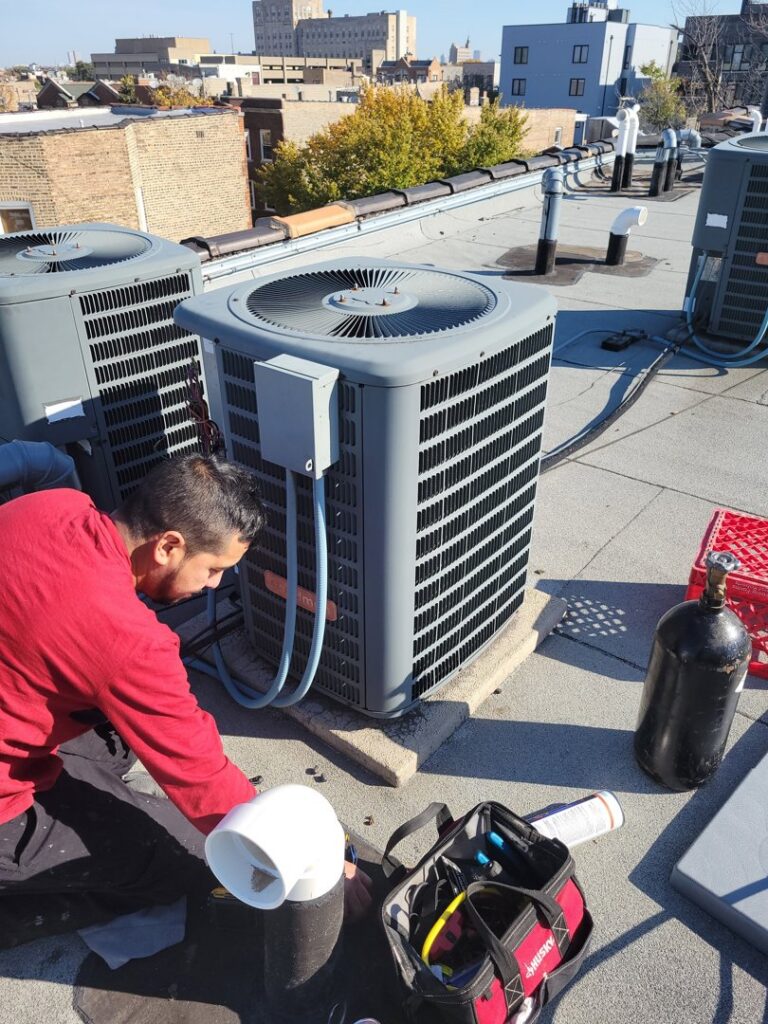 An HVAC technician performing service on a rooftop AC unit for Brothers Heating & Cooling Inc. in Chicago, IL.