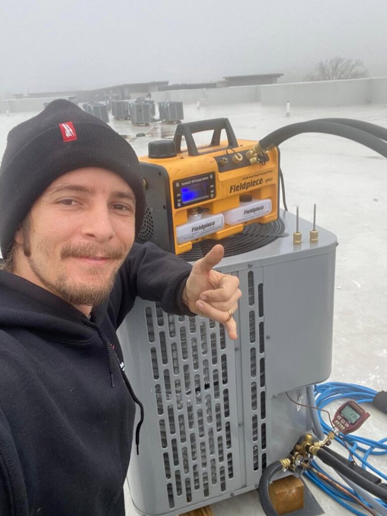 An HVAC technician servicing a rooftop commercial HVAC unit with diagnostic equipment for Stanton Home Comfort in Fordland, MO.
