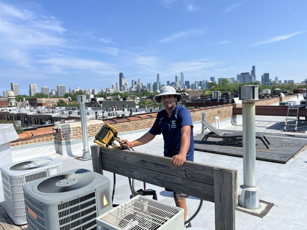 An HVAC technician performing rooftop service with the Chicago skyline in the background for Modern HVAC Technology in Chicago, IL.
