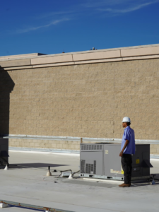 An HVAC technician inspecting a large commercial rooftop unit for Blue Collar HVAC in Henderson, NV.