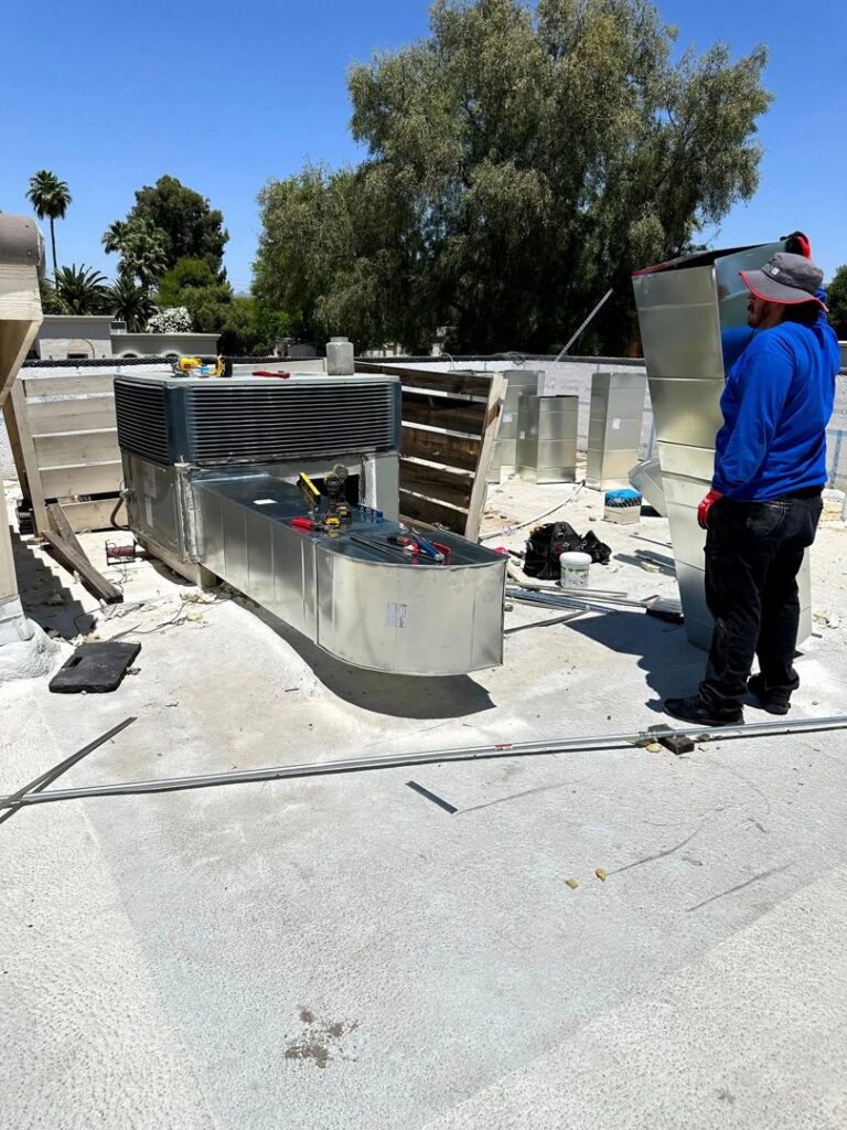 An HVAC technician working on a rooftop unit with new ductwork installation by BH cooling & Heating in Glendale, AZ.