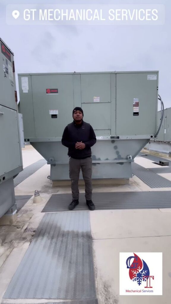 An HVAC technician from GT Mechanical Services standing in front of a commercial rooftop unit in Baltimore, MD