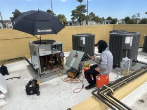 An HVAC technician servicing a rooftop unit with tools and gauges for Gotham Air LLC in Glendale, AZ.