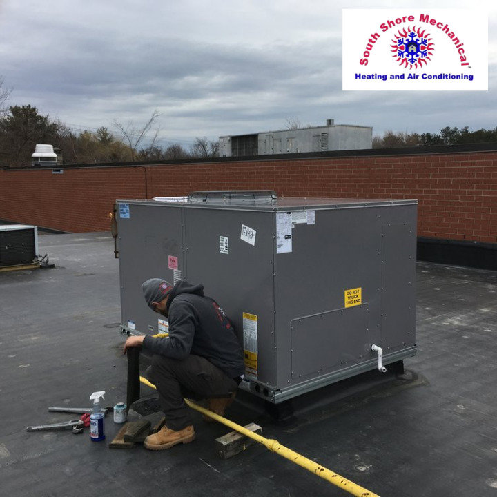 An HVAC technician performing service on a commercial rooftop unit for South Shore Mechanical in Abington, MA