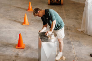 An HVAC technician carefully sealing ductwork with tape during an installation for Wingman Heating + Cooling in Auburn, AL.