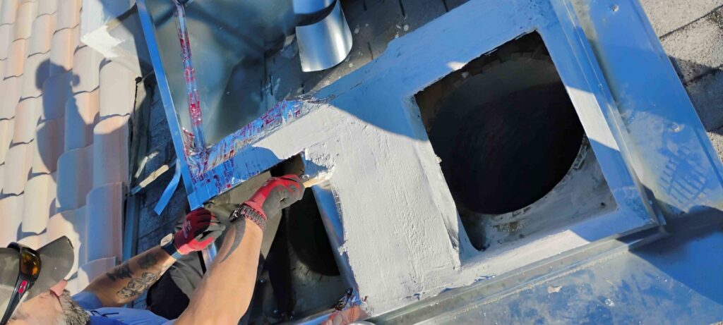 An HVAC technician applying sealant to a rooftop HVAC unit or ductwork for Bishop Air Service in Henderson, NV.