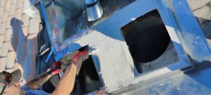 An HVAC technician applying sealant to a rooftop HVAC unit or ductwork for Bishop Air Service in Henderson, NV.