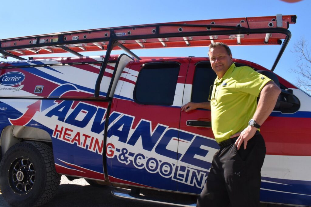 An Advanced HVAC and Plumbing technician standing next to a company service truck in Morgantown, WV.