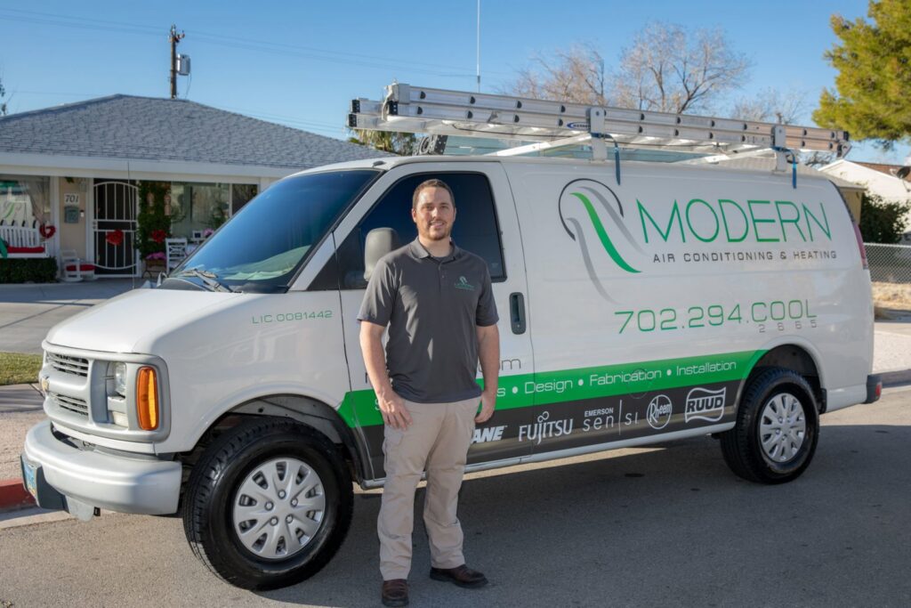An HVAC technician standing in front of a Modern Air Conditioning & Heating service van in Boulder City, NV.