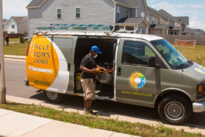 An HVAC technician from Nashville Solutions preparing for a job next to a branded service van in Nashville, TN