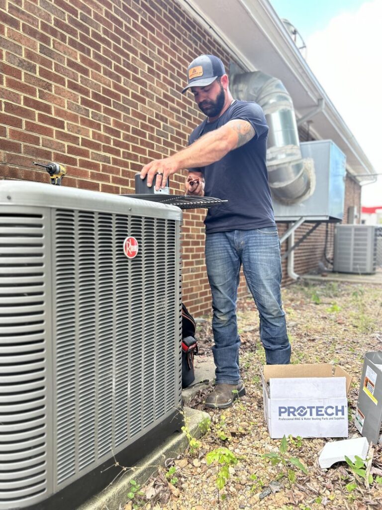 An HVAC technician servicing an outdoor AC condenser unit for Anderson's Air in Newport News, VA