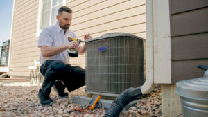 An HVAC technician servicing an outdoor air conditioning unit for Absolute Plumbing, Electrical, Heating & Air in Denver, CO