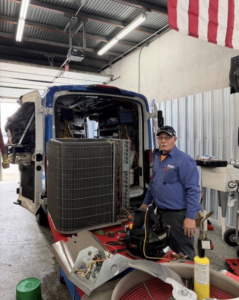 An HVAC technician servicing an outdoor AC unit from a service van at Advantage Plumbing Heating & Air in Vandalia, OH.