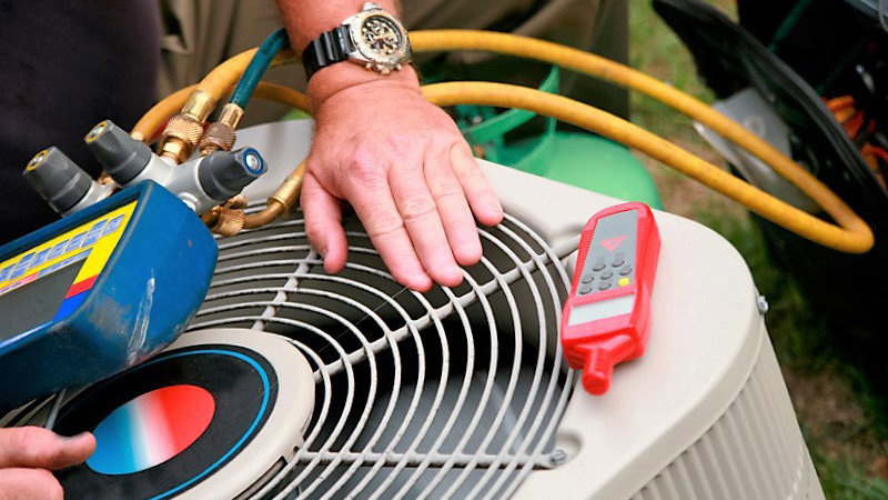 An HVAC technician servicing an outdoor air conditioning unit with tools for Airtechservicesohio.com in Columbus, OH