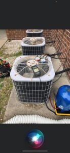 An HVAC technician servicing an outdoor AC condenser unit with gauges and tools for All American Heating Air & More LLC in Wilson, NC.