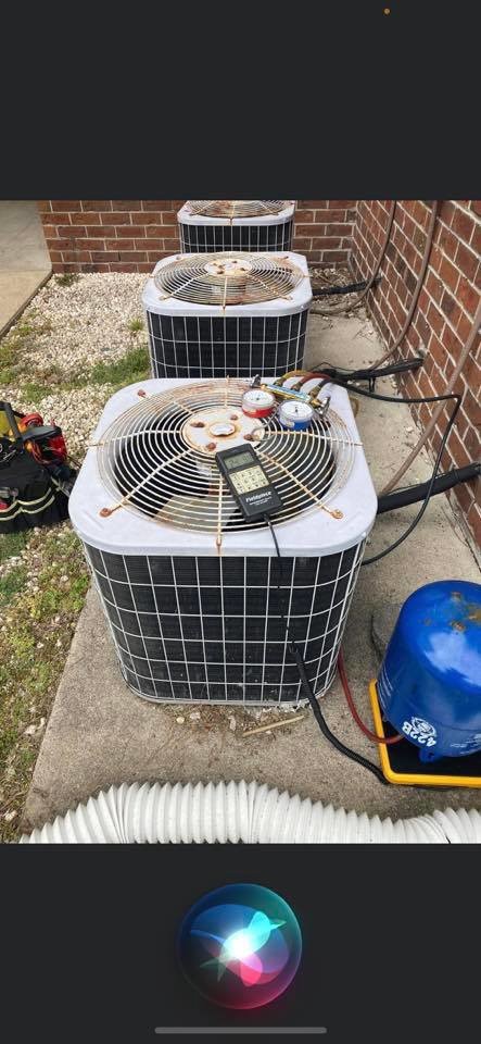 An HVAC technician servicing an outdoor AC condenser unit with gauges and tools for All American Heating Air & More LLC in Wilson, NC.