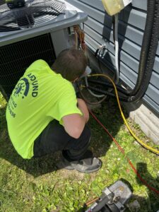An HVAC technician from All Around Heating & Cooling servicing an outdoor air conditioning unit in Akron, OH.