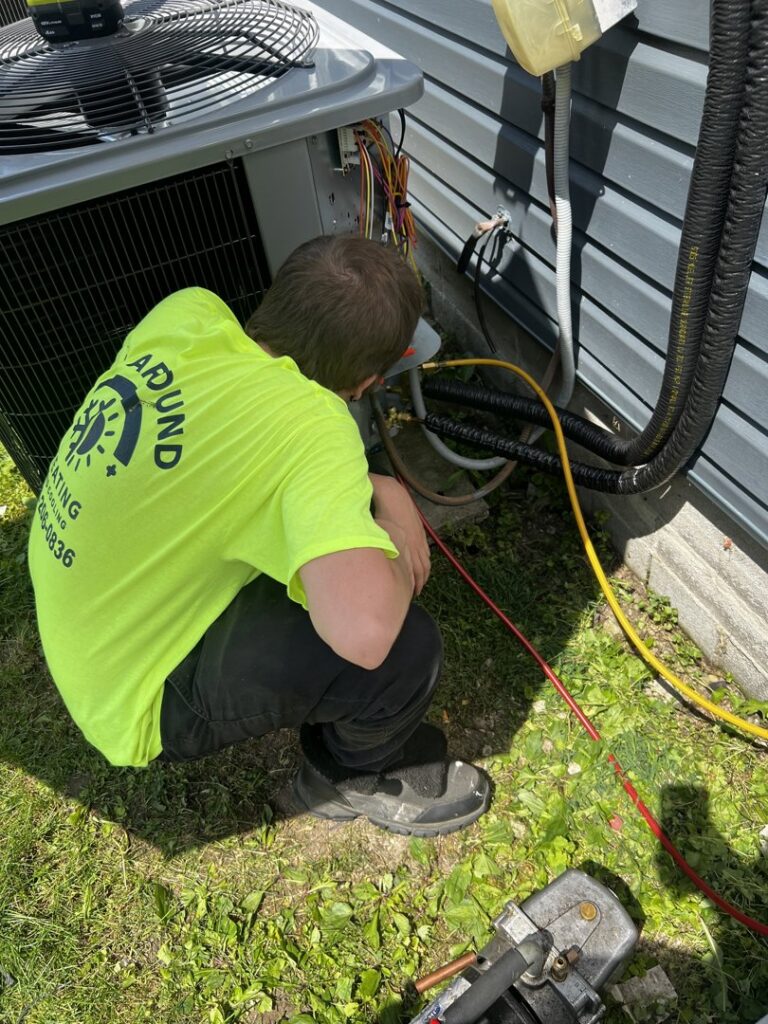 An HVAC technician from All Around Heating & Cooling servicing an outdoor air conditioning unit in Akron, OH.