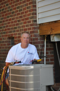 An HVAC technician from All Comfort Air Heating and Air Conditioning servicing an outdoor AC unit in Raleigh, NC.