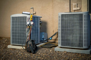 An HVAC technician servicing an outdoor AC unit with gauges and tools at AVI Heating & Cooling in Surprise, AZ.
